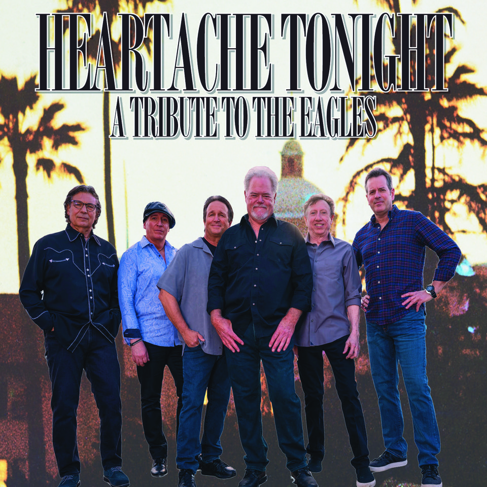 Six men stand together in front of a backdrop with palm trees and a domed building. Text above reads, HEARTACHE TONIGHT: A TRIBUTE TO THE EAGLES. The group appears to be a tribute band.